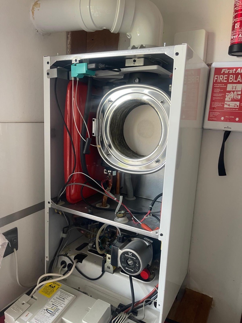 A boiler with its casing open for diagnosis, heat exchanger and internal components exposed
