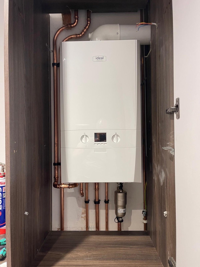 An Ideal combi boiler installed in a wood-panelled airing cupboard